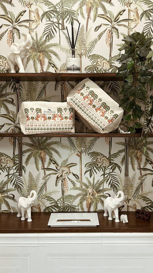 Decorative shelf  in the downstairs loo with cotton wash bags and small sculptures against a tropical wallpaper background