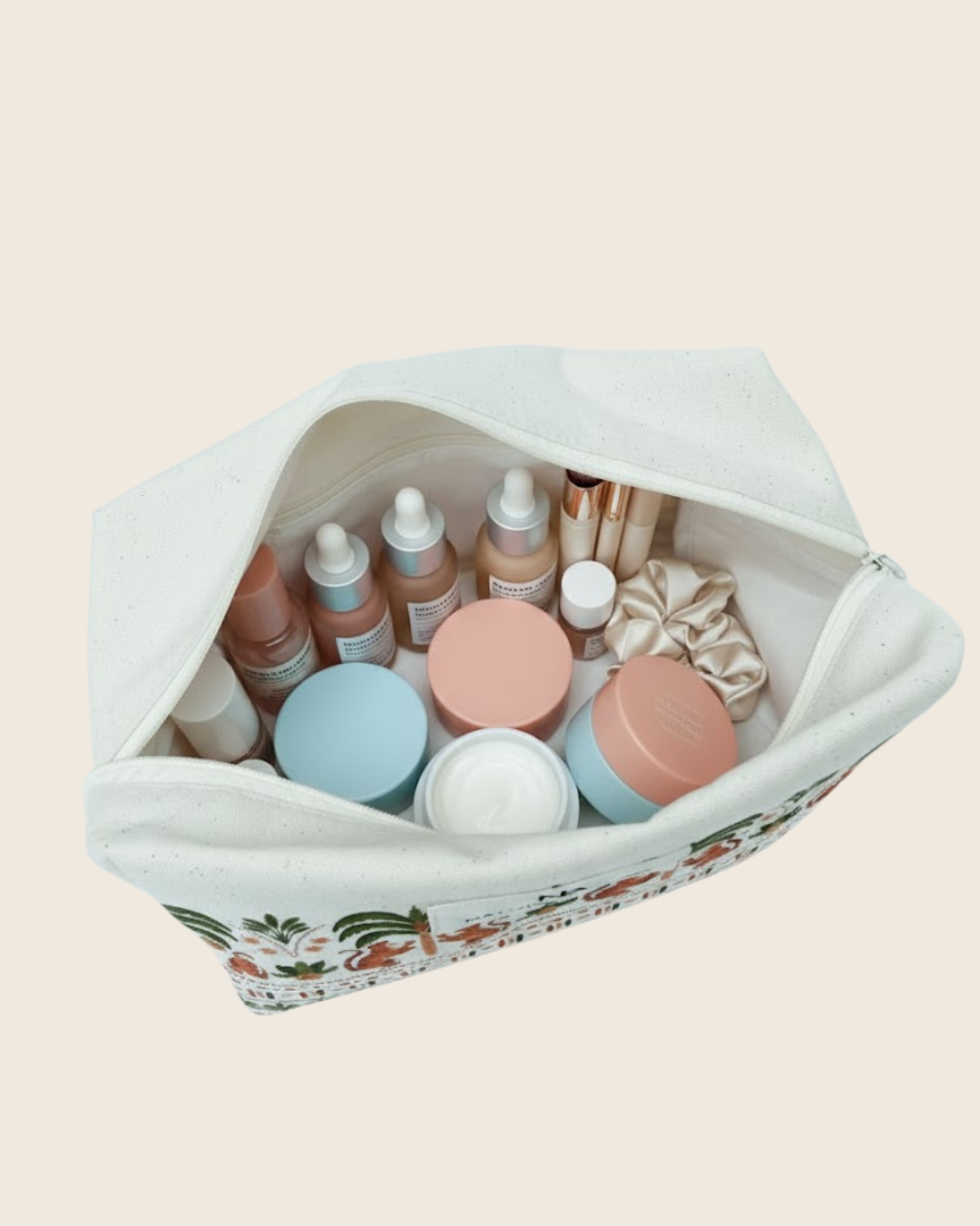 Set of skincare products in a tiger print toiletry bag on a light pink background