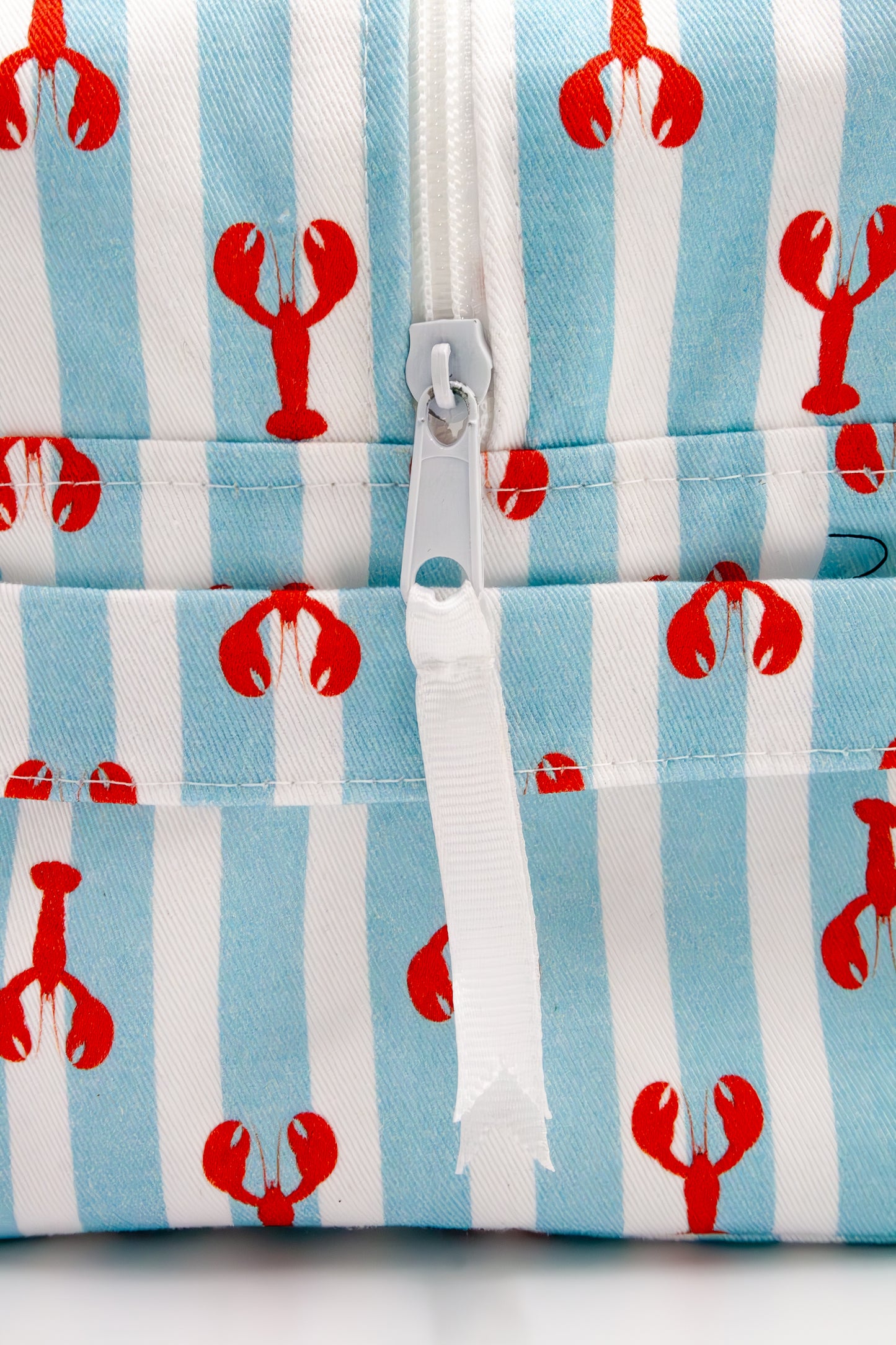 Wash bag with red lobster pattern on blue and white striped background with puller