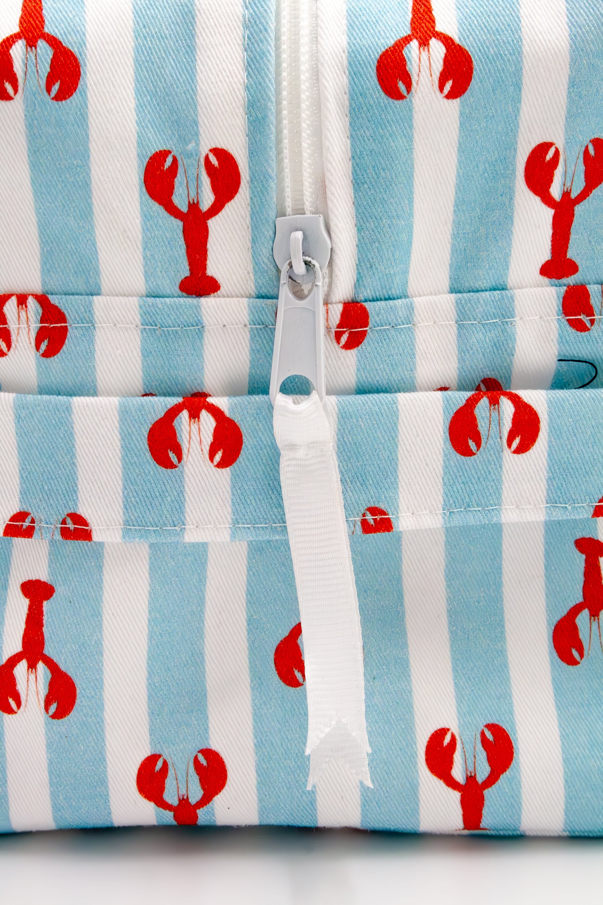 Wash bag with red lobster pattern on blue and white striped background with puller