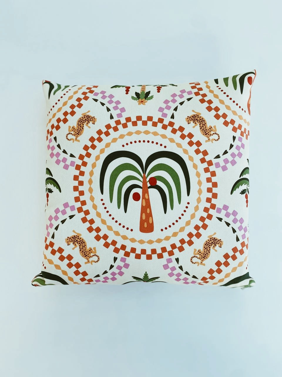 Decorative pillow with a colorful  palm tree pattern on a light blue background