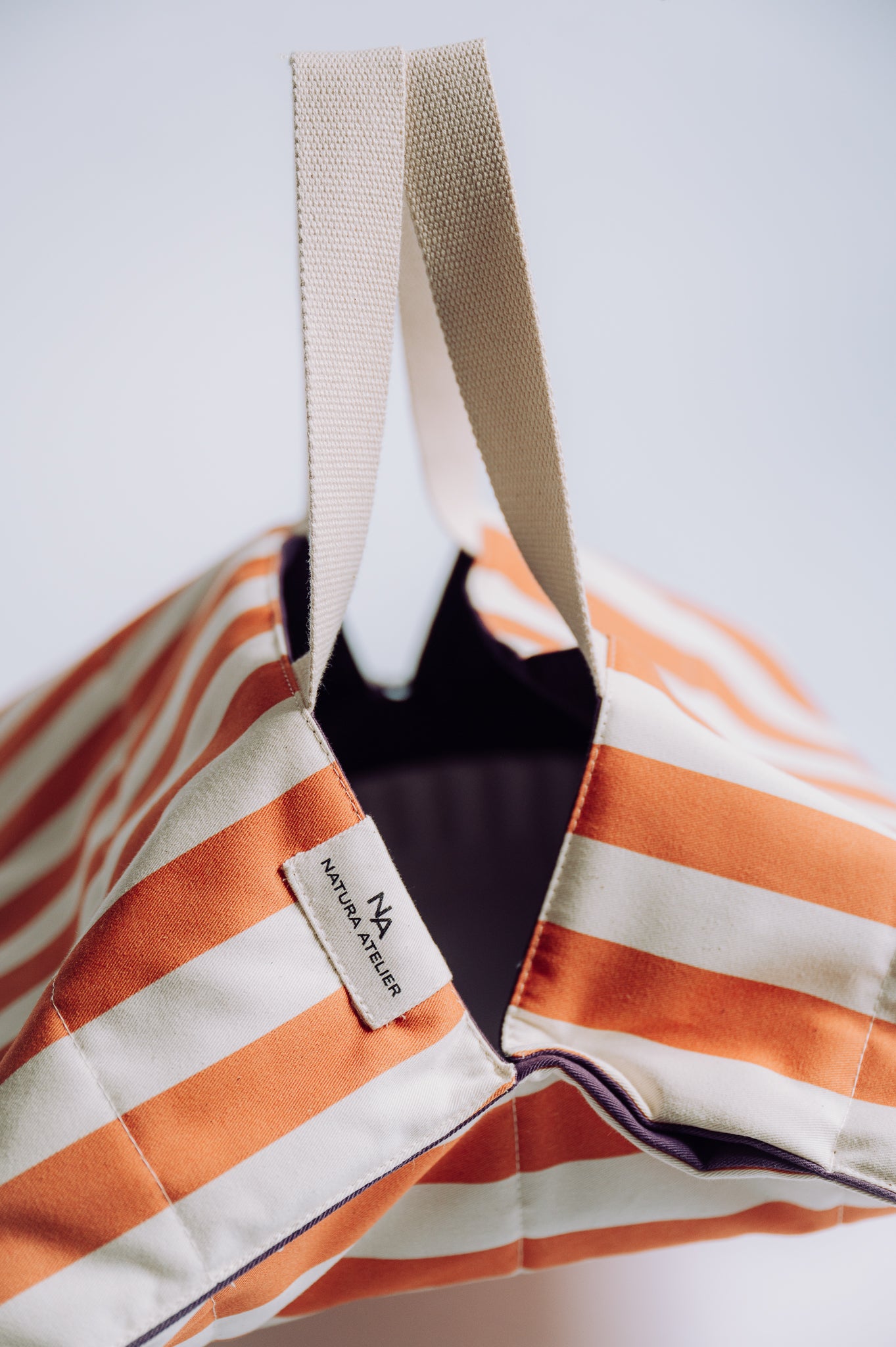 Striped bag with a visible Natura Atelier brand label on a light background