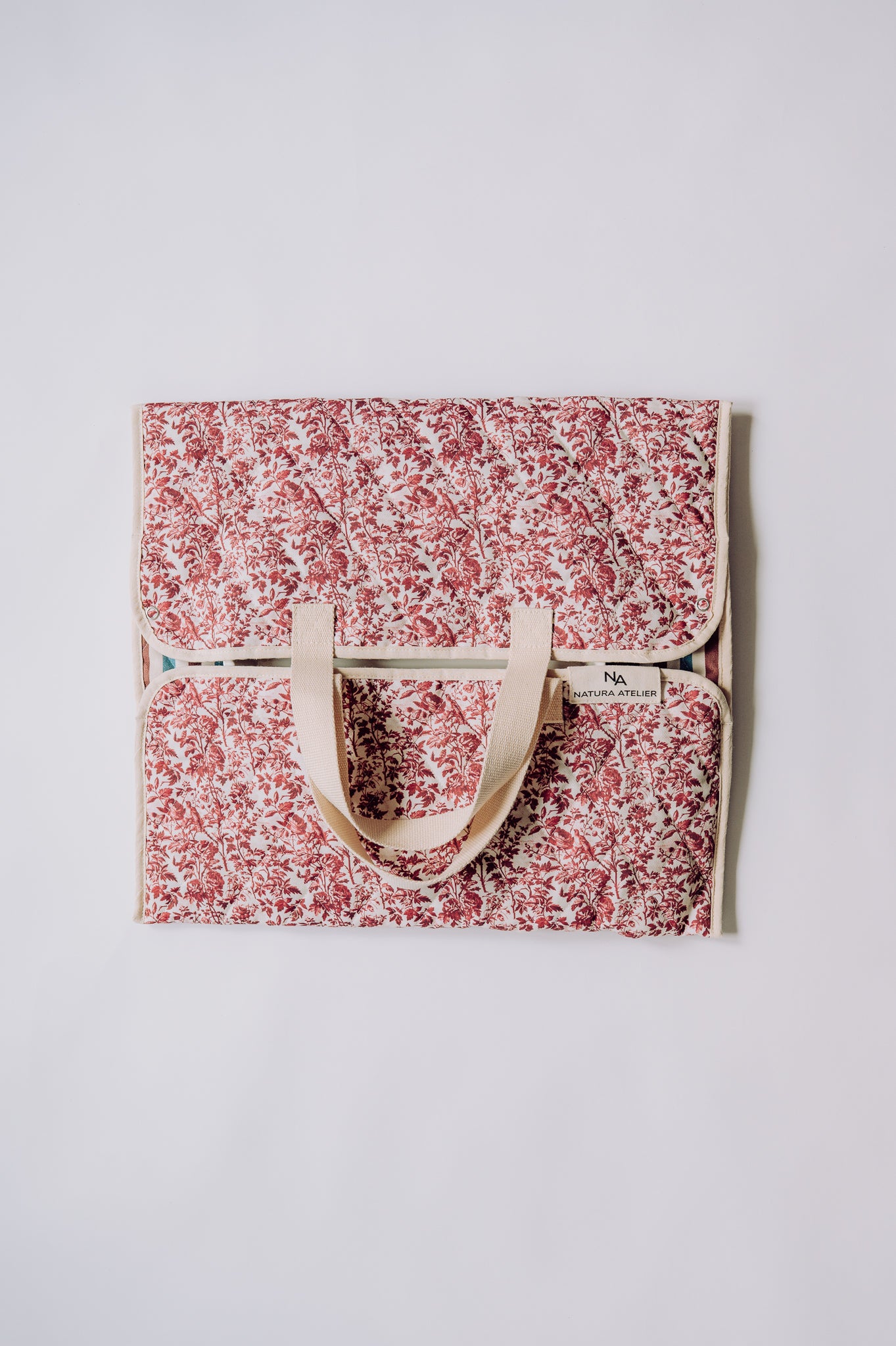 Floral -patterned bag with a cotton webbing handle on a light gray background