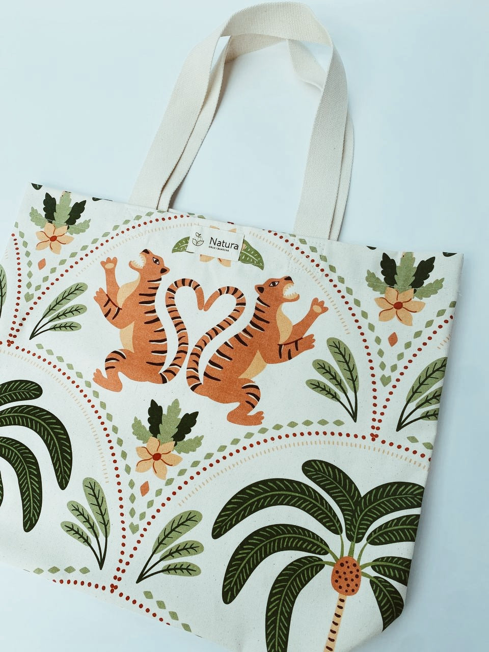 Tote bag with tiger design and nature-themed elements on a light blue background